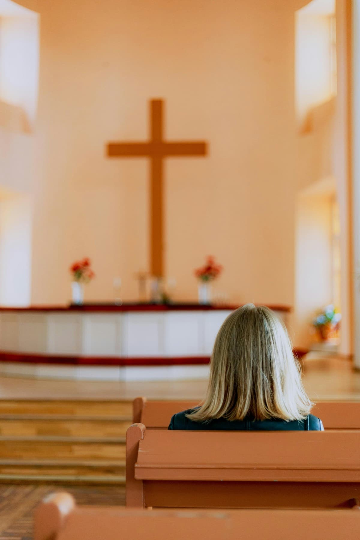 A woman sitting in a wooden church pew