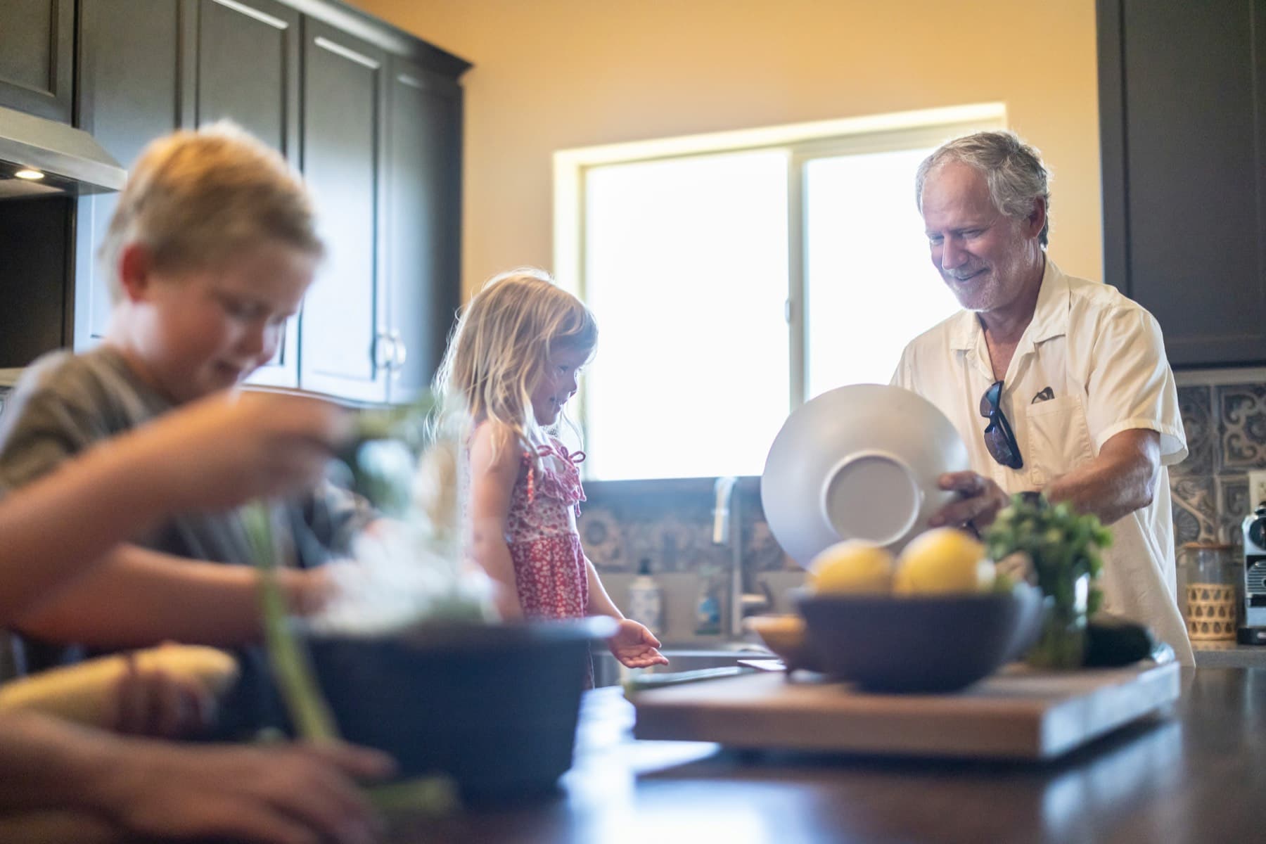 A grandfather and grandchildren preparing food in a kitchen