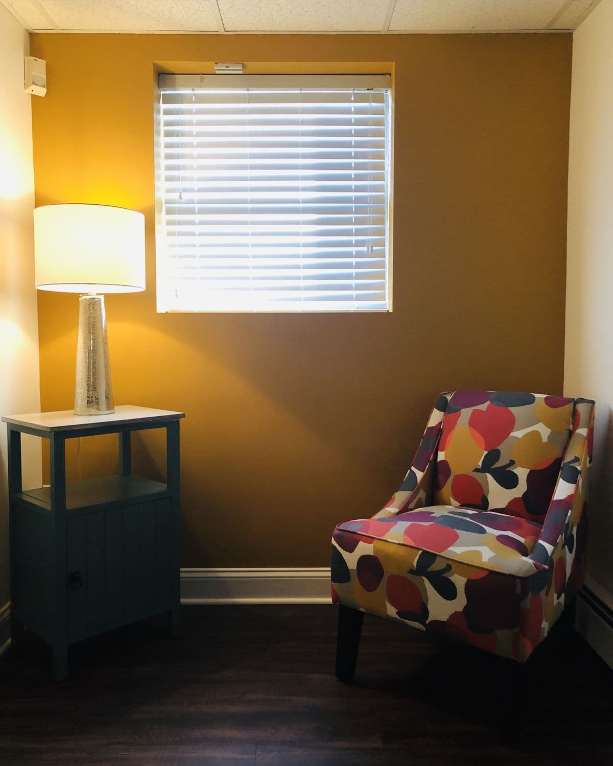 A corner of our Springfield office: a lamp, a patterned armchair, and warm light through the blinds